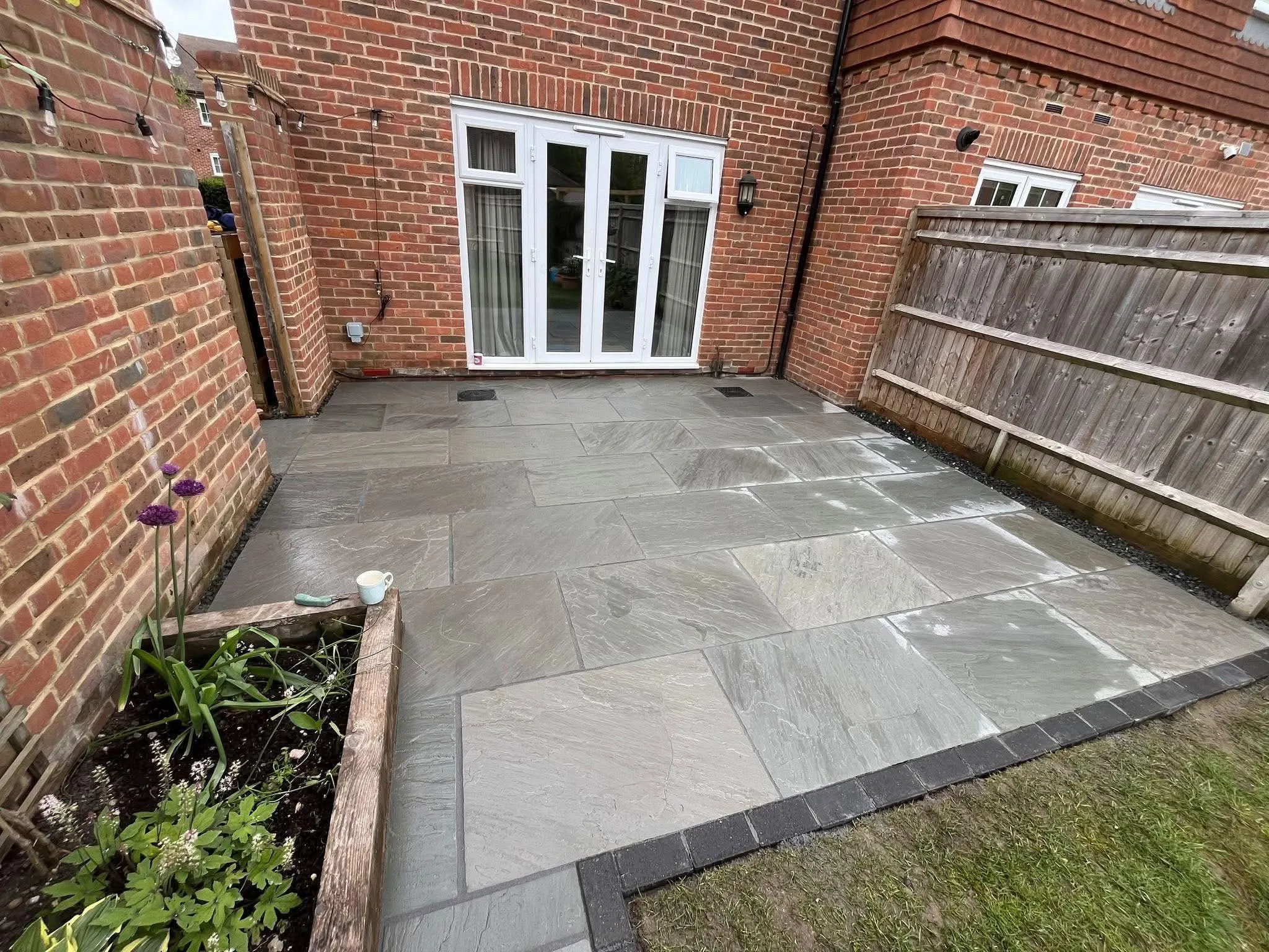 Grey sandstone patio with brick border flowerbed