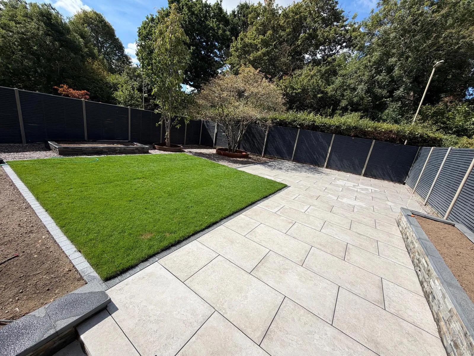 Porcelain patio with raised beds and dark fencing